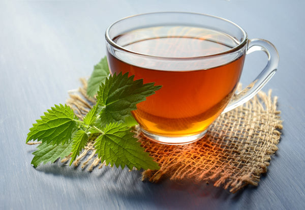 Close-up of green tea leaves and a warm cup of tea